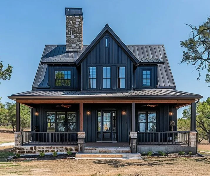 A beautiful two-story black barndominium with a covered porch